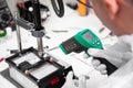 The master measures the temperature of the microchip at the soldering station with a laser thermometer. Service center. Repair of