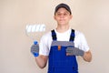 Master painter plasterer in overalls holds a roller in his hand. Blue jumpsuit with shoulder straps. Royalty Free Stock Photo