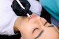 Master of permanent makeup in a black glove holds marking pencils in front of the model`s lips Royalty Free Stock Photo