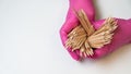 Master in pink gloves holds orange sticks for manicure.