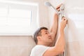 A master plumber installs a shower head in the bathroom.