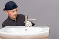 The master plumber screws the faucet to the sink in the bathroom