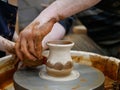 The master Potter helps the child to paint a clay jug with white paint on a modern Potter`s wheel with an electric drive. Royalty Free Stock Photo