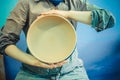 Potter holds round clay plate in his hands.