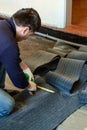 The master prepares a bituminous tape for installation, protection of a floor against moisture. Royalty Free Stock Photo