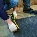 The master prepares a bituminous tape for installation, protection of a floor against moisture. Royalty Free Stock Photo
