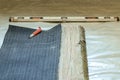 The master prepares a bituminous tape for installation, protection of a floor against moisture. Royalty Free Stock Photo