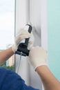 Master in protective gloves, fills the gap with silicone to seal the installation of a plastic window, close-up