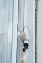 Master in protective gloves, fills the gap with silicone to seal the installation of a plastic window, from the street