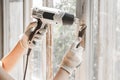 Master removes old paint from window with heat gun and scraper. Closeup. Royalty Free Stock Photo