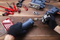 The master repairs a broken electrical device: drill, cutter on a wooden table. Electric Tool Repair Shop