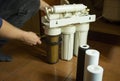 The master replaces dirty filters in the home water purification system. Human hands, filter, membrane