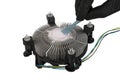 a master\'s hand applies thermal paste to a CPU fan cooler with an aluminum radiator and a copper core