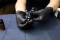 Master tattoo artist holds a tattoo machine in front of him to prepare for drawing up a disposable cartridge in it Royalty Free Stock Photo