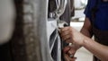 Car wheel replacement in workshop, self service tire fitting concept, handyman uses professional wrench to tighten wheel