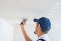 A master in uniform puts putty on the caps of self-tapping screws for fixing plasterboard sheets on the ceiling Royalty Free Stock Photo
