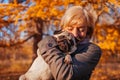 Master walking pug dog in autumn park. Happy woman hugging pet. Friendship between human and animal Royalty Free Stock Photo