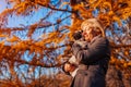 Master walking pug dog in autumn park. Happy woman hugging pet. Royalty Free Stock Photo