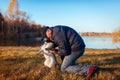 Master walking pug dog in autumn park by river. Happy man hugging pet outdoors Royalty Free Stock Photo