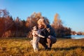 Master walking pug dog in autumn park by river. Happy woman hugging and kissing pet. Royalty Free Stock Photo