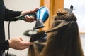 Master woman hairdresser dries the girl& x27;s hair with a hairdryer and combs after washing in the beauty salon Royalty Free Stock Photo