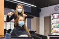 Master woman hairdresser in a medical mask dries the girl& x27;s hair with a hairdryer and combs after washing in a beauty Royalty Free Stock Photo