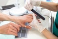 Master woman manicurist prepares nails for applying gel polish on client`s hands. Background