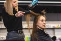 Master woman hairdresser dries the girl& x27;s hair with a hairdryer and combs after washing in the beauty salon. Royalty Free Stock Photo