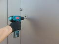 Hand 's man with screwdriver. The worker installs a door lock in the front door, metal doors with a polymer coating using an
