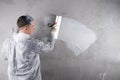 The master works on leveling the concrete wall, a large spatula, applies a white solution, there is a place for the inscription,