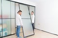 masters install sliding doors of wardrobe made of metal and glass. Royalty Free Stock Photo