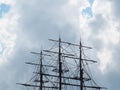 The masts of the ship with ropes and without sails against the background of the sky and clouds. Fragment of a sailing Royalty Free Stock Photo