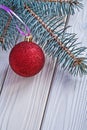 Mat red christmas ball and pinetree branch on white wooden board