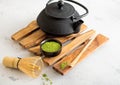 Matcha green organic tea powder with iron cast kettle with bamboo whisk and spoon on wooden tray on white Royalty Free Stock Photo