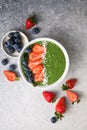 Matcha green tea breakfast superfoods smoothies bowl topped with strawberries, blueberries, coconut flakes Overhead, top view,