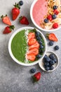 Matcha green tea breakfast superfoods smoothies bowl topped with strawberries, blueberries, coconut flakes Overhead, top view,