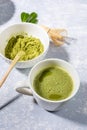 Matcha green tea in cup, matcha green tea powder, wooden spoon, bamboo whisk, fresh leaves on grey textured backdrop. Royalty Free Stock Photo