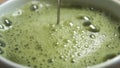 Matcha green tea frothing with frother in slow motion with a bubble swirl.