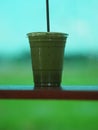 Matcha Green tea put milk ice in plastic glasses set on a wooden plate blurred of nature background Royalty Free Stock Photo