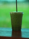 Matcha Green tea put milk ice in plastic glasses set on a wooden plate blurred of nature background Royalty Free Stock Photo