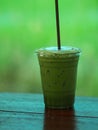 Matcha Green tea put milk ice in plastic glasses set on a wooden plate blurred of nature background Royalty Free Stock Photo