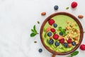 Matcha green tea smoothie bowl with fresh fruits, berries, nuts, seeds and oat granola for healthy vegan breakfast Royalty Free Stock Photo