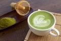 Matcha latte art heart shape on top on wooden table with some gr