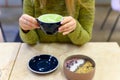 Matcha latte Cup of green tea and smoothie bowl of raw food on the table and a woman ready to drink Royalty Free Stock Photo