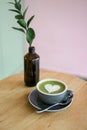 Matcha Latte heart shaped art in a grey cup on a brown table with pastel background