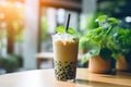 Matcha milk shake with tapioca sweet balls, asian trendy iced drink bubble tea on wooden table in cafe.