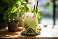 Matcha milk shake with tapioca sweet balls, asian trendy iced drink bubble tea on wooden table in cafe.