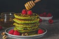 Matcha tea green pancakes. Pile of homemade pancakes with fresh raspberries, pistachios and flowing honey. low key Royalty Free Stock Photo