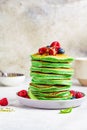 Matcha tea pancakes with berries, white background, vertical. Healthy vegan food concept Royalty Free Stock Photo