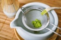 Matcha tea powder in sieve on white clay tea bowl, Matcha bamboo whisk and accessories, Green tea making set, Royalty Free Stock Photo